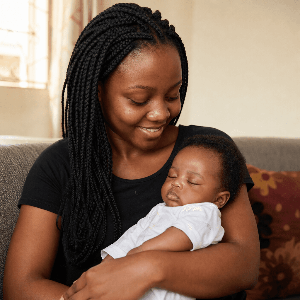 Mother with braids holding her sleeping baby