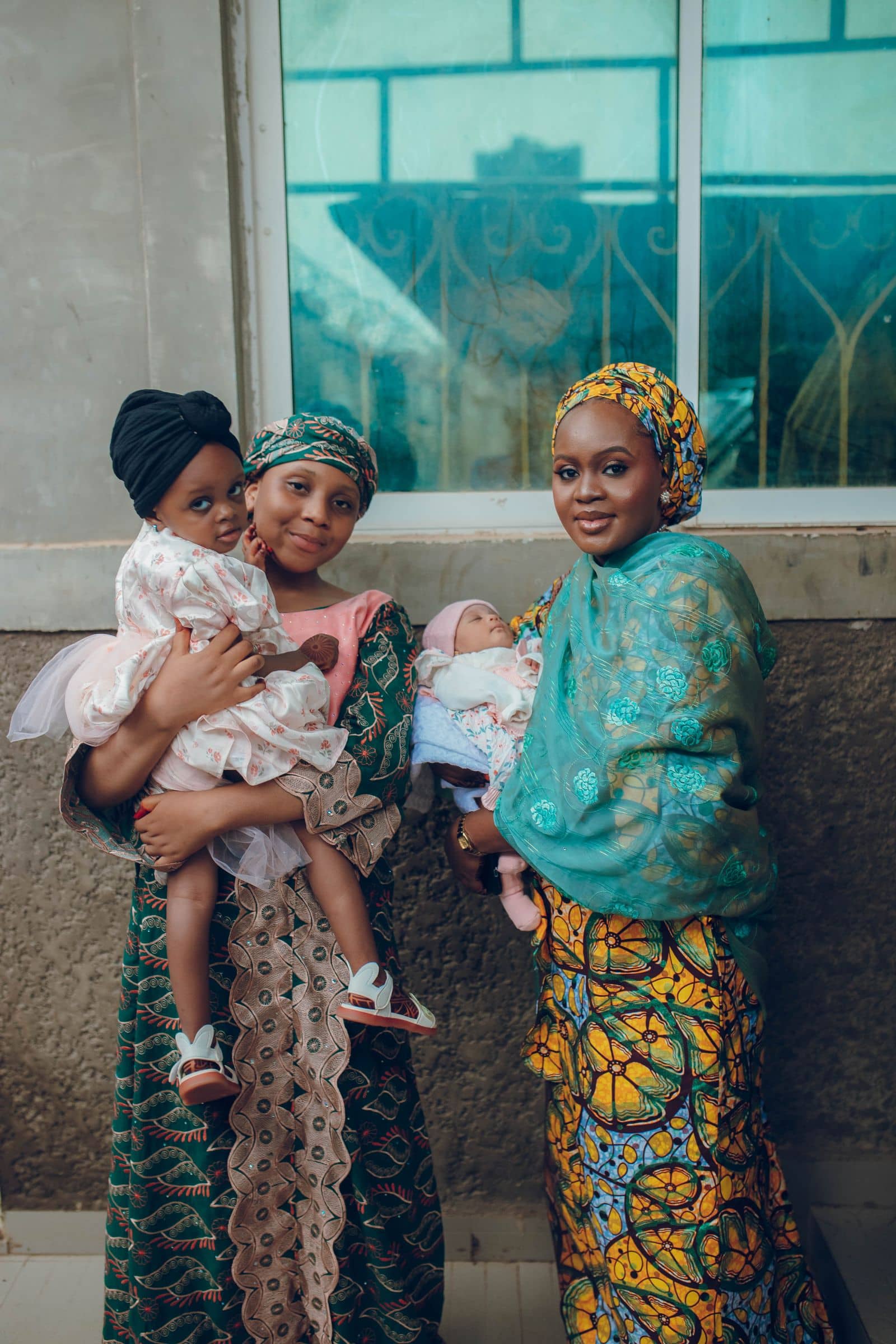 Two mothers in gele holding their children